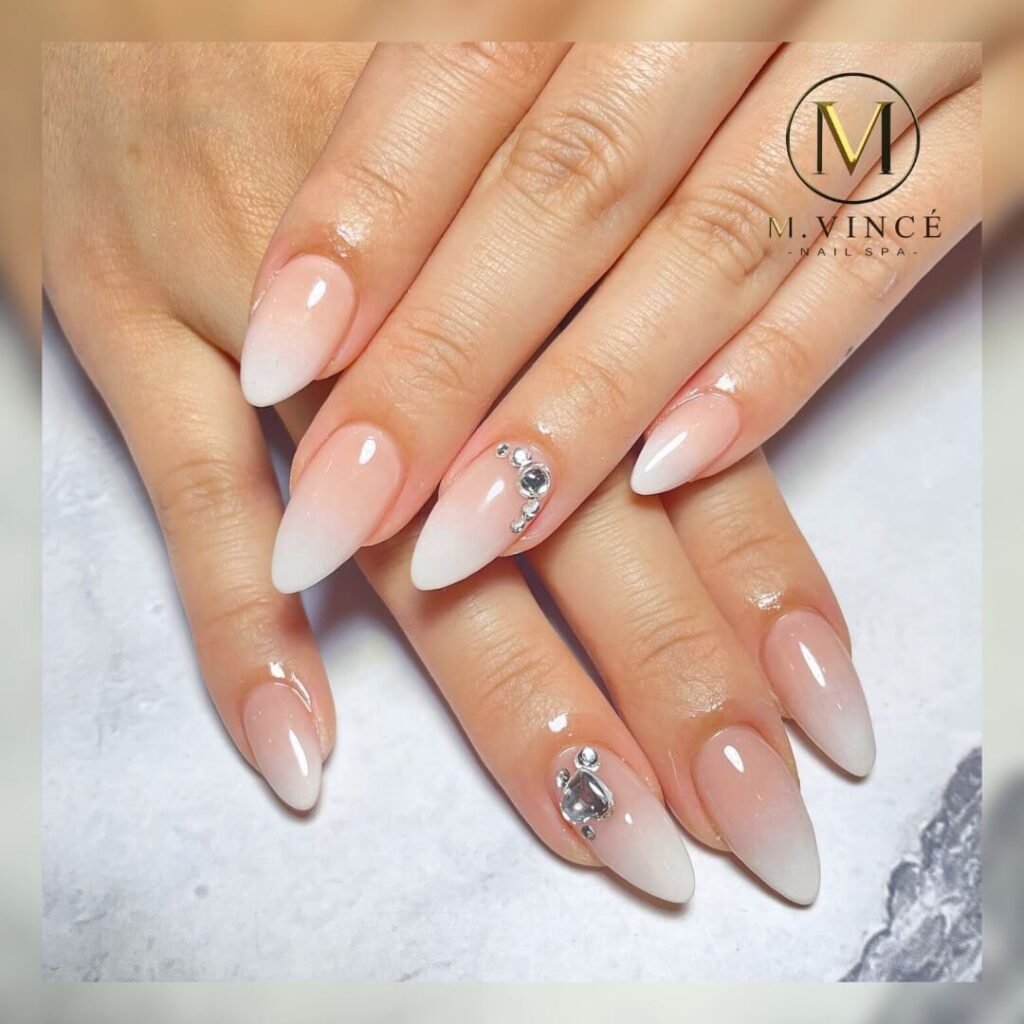 Almond-shaped nails with a gradient fade from white to pastel pink by m.vincenailspa