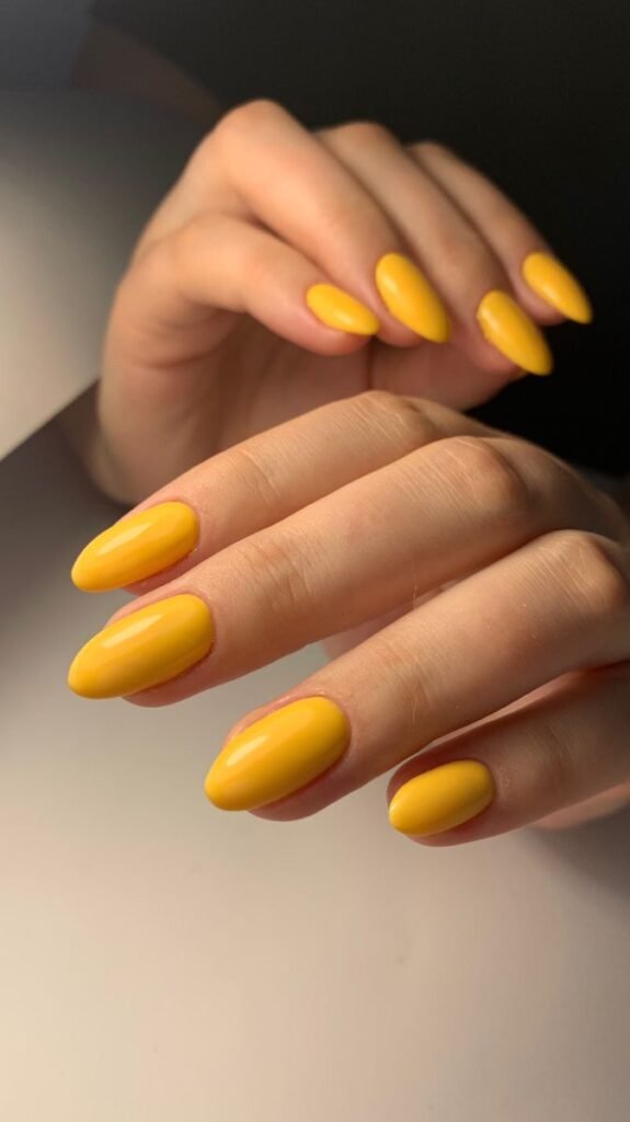 Glossy lemon-yellow nails against a white background by nailbeautyguide