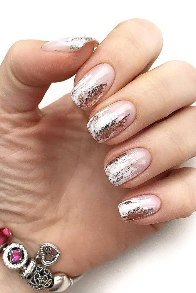 Gold foil flakes scattered unevenly over a glossy white base by nailbeautyguide