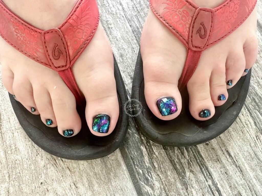 Mystical photo of dark galaxy toe nails with glitter stars against starry night sky backdrop by lakeoswegonails
