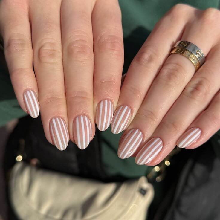 Thin black stripes running diagonally across glossy white nails by nailbeautyguide