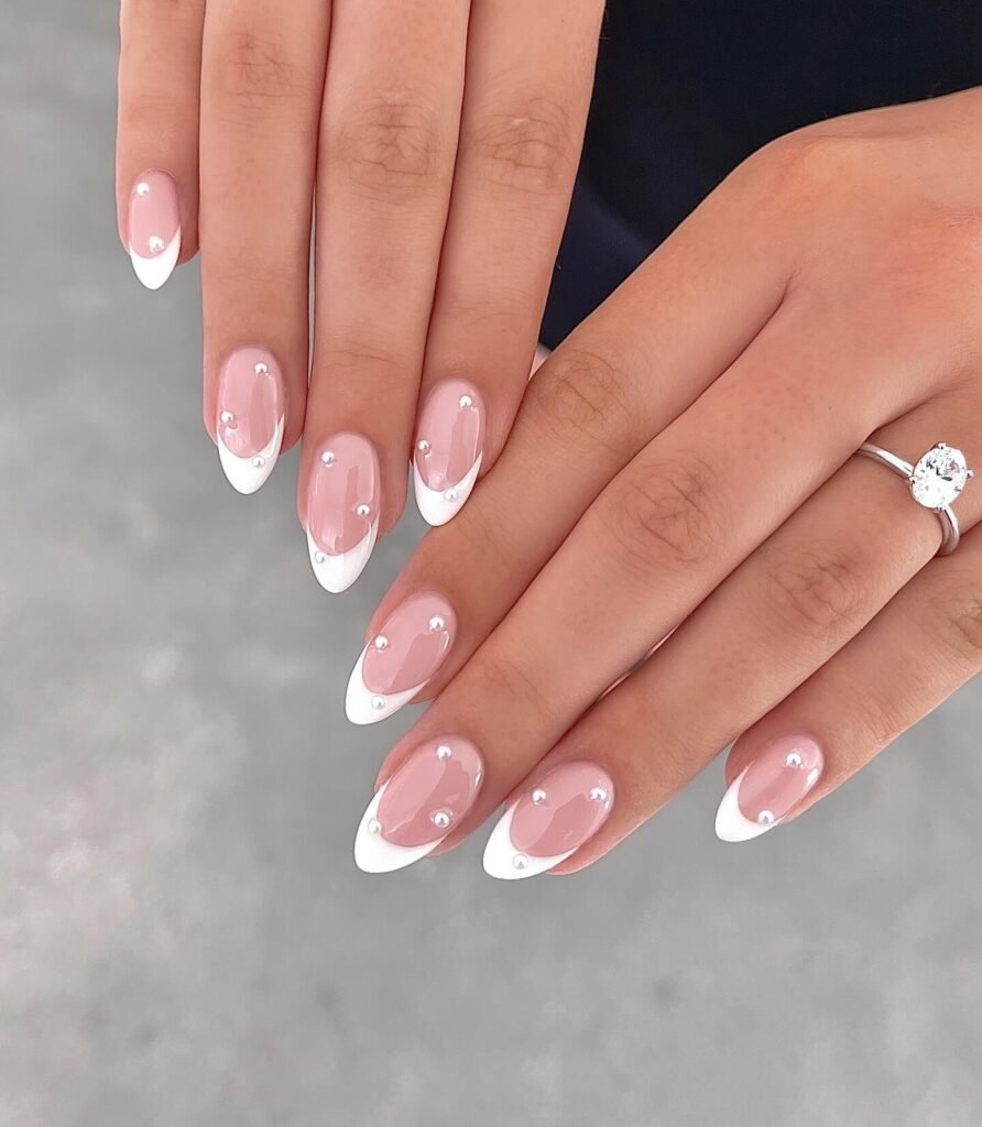 A timeless white French tip manicure paired with delicate gold rings by peachinails