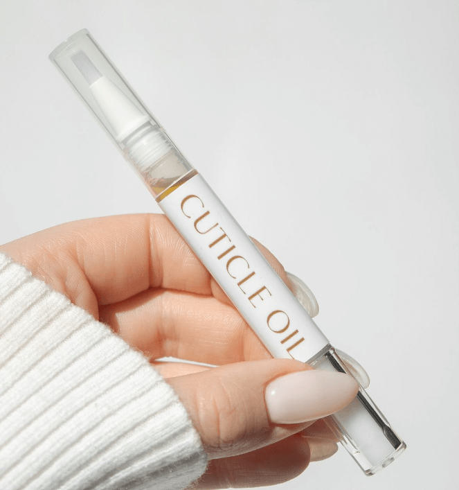 A woman massaging cuticle oil into her nails by nailbeautyguide