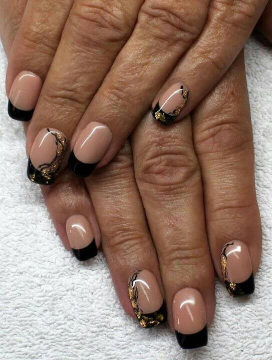 Almond-shaped nails with scattered gold foil over black tips by nailbeautyguide