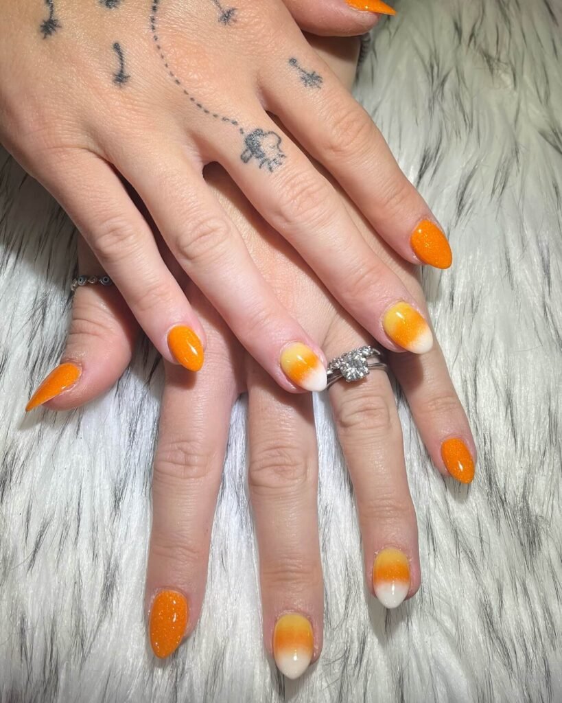 Candy corn-inspired October nails with orange, yellow, and white by simplynailsbabylon