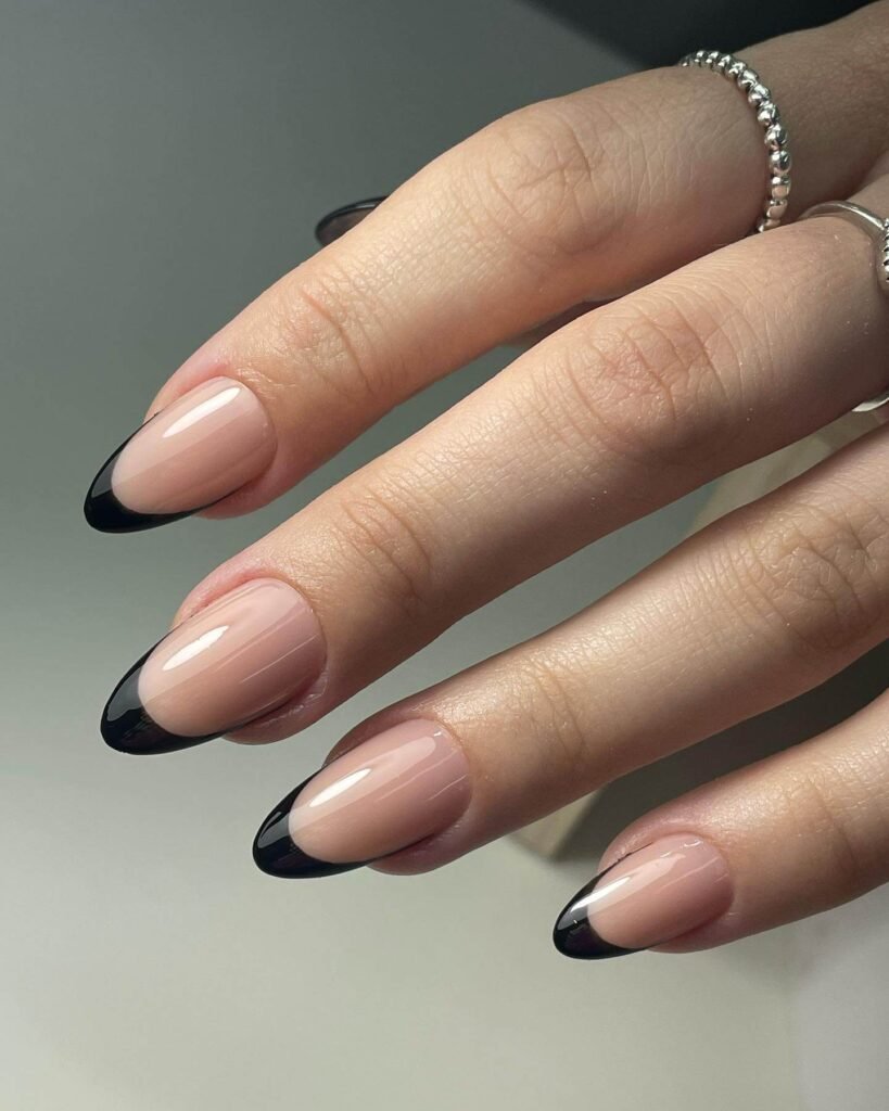 Close-up of almond-shaped nude nails with shiny black tips by bylolalita