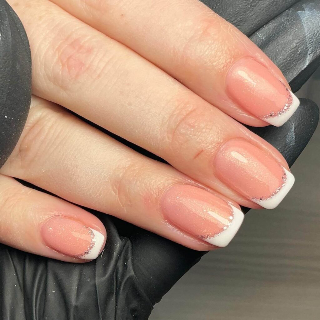 Sparkling glitter French tips shining under soft lighting by ohprettypolish.uk