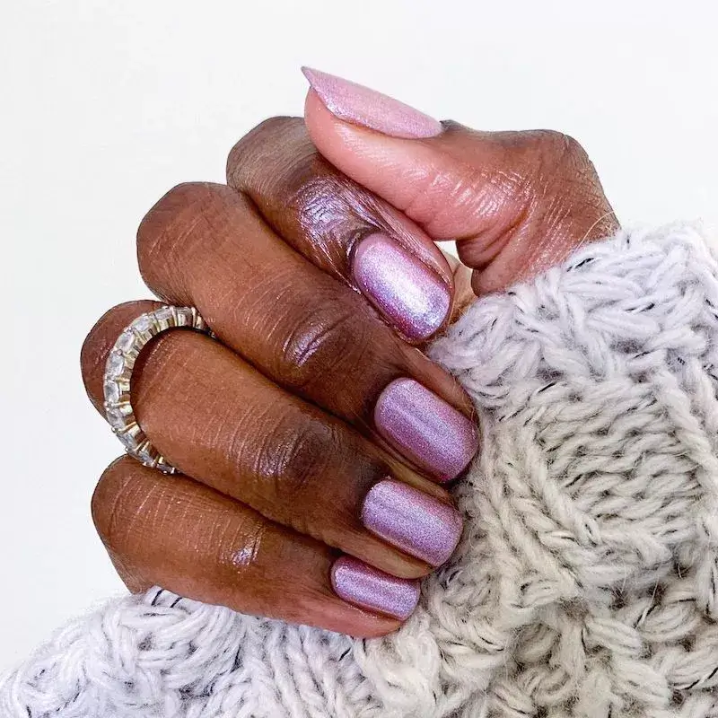 A hand with a soft, muted mauve nail polish on almond-shaped nails by oliveandjune