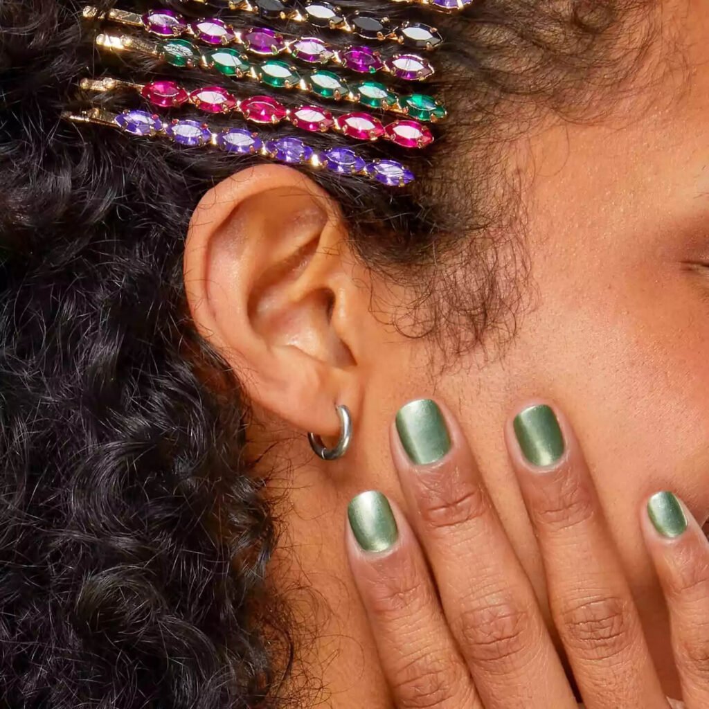 Nails with a festive, shimmery green polish that suggests mistletoe by essie
