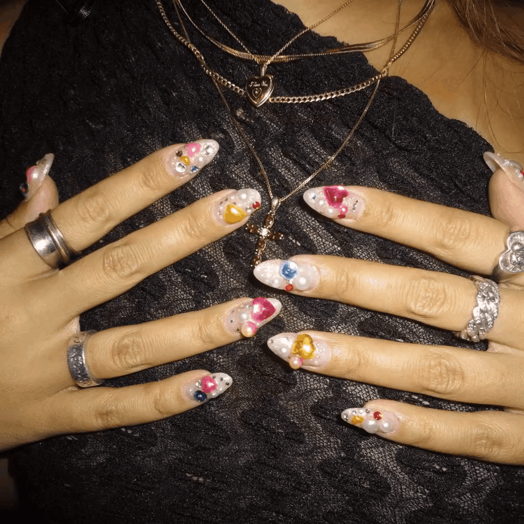 Almond nails with large 3D charms, pearls, and heart accents. by gotg0ld