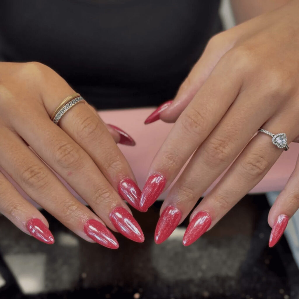 Bold red nails with a reflective chrome finish. by brushednailsalon