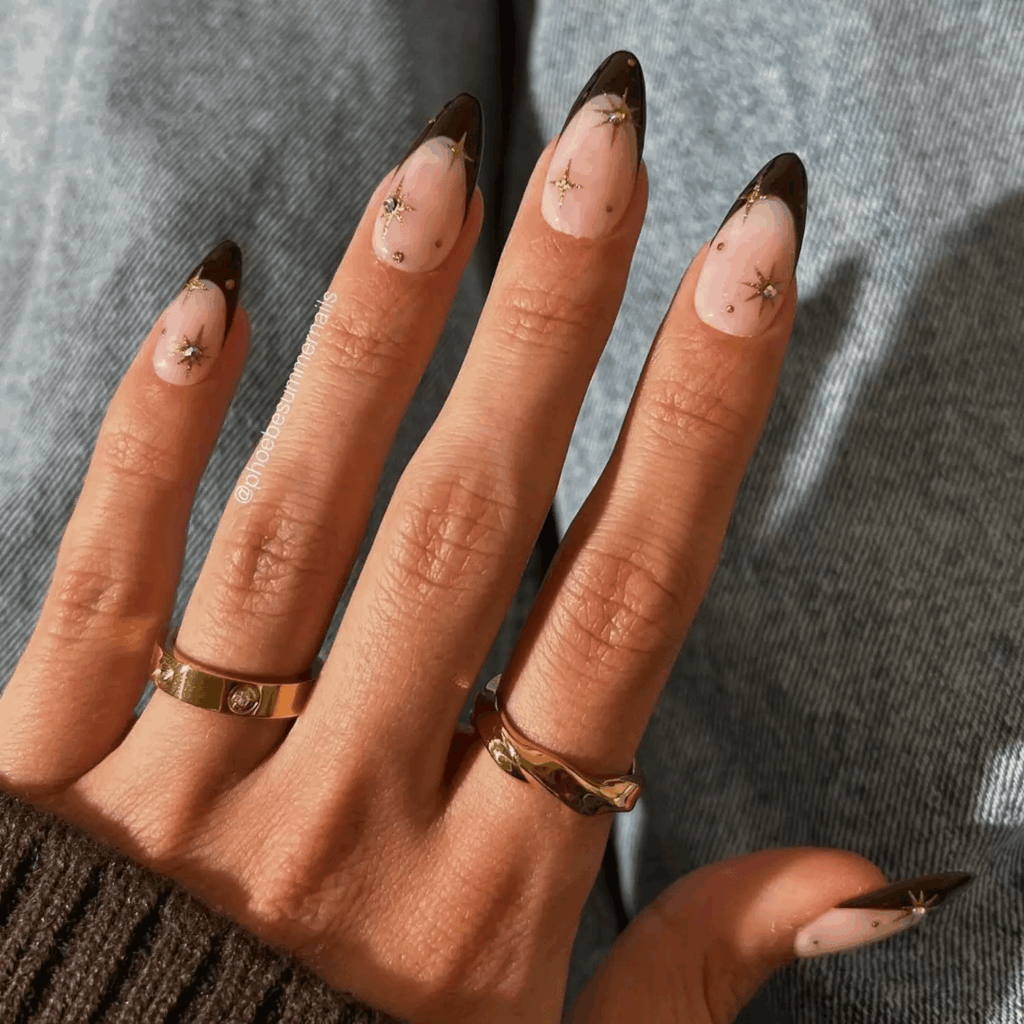 Brown French tips on a nude base with gold starbursts and dots. by phoebesummernails
