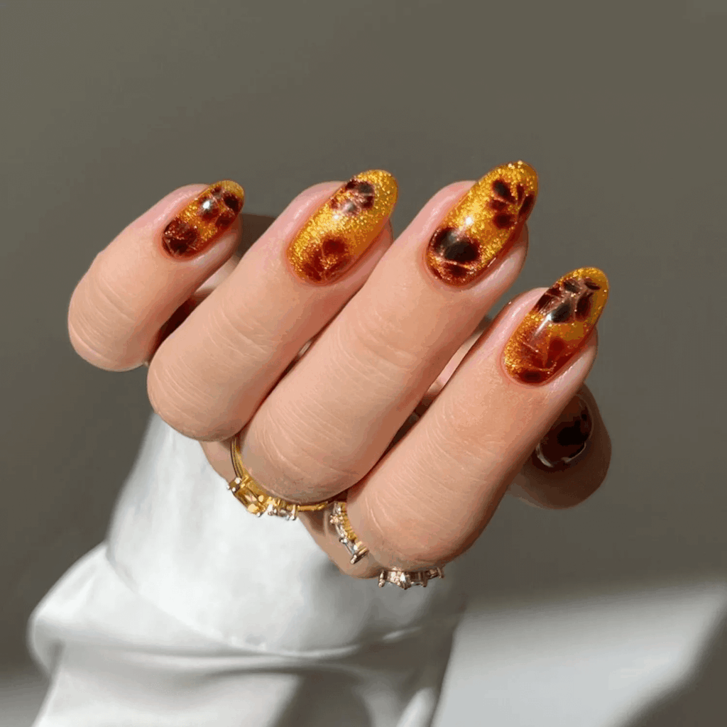Sparkly amber nails with espresso-colored leaf print details. by heygreatnails