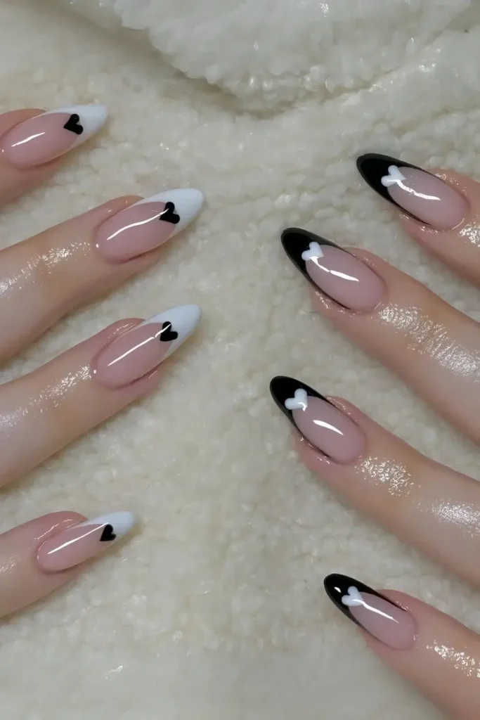 Alternating black and white French tips with contrasting heart colors. by nailbeautyguide