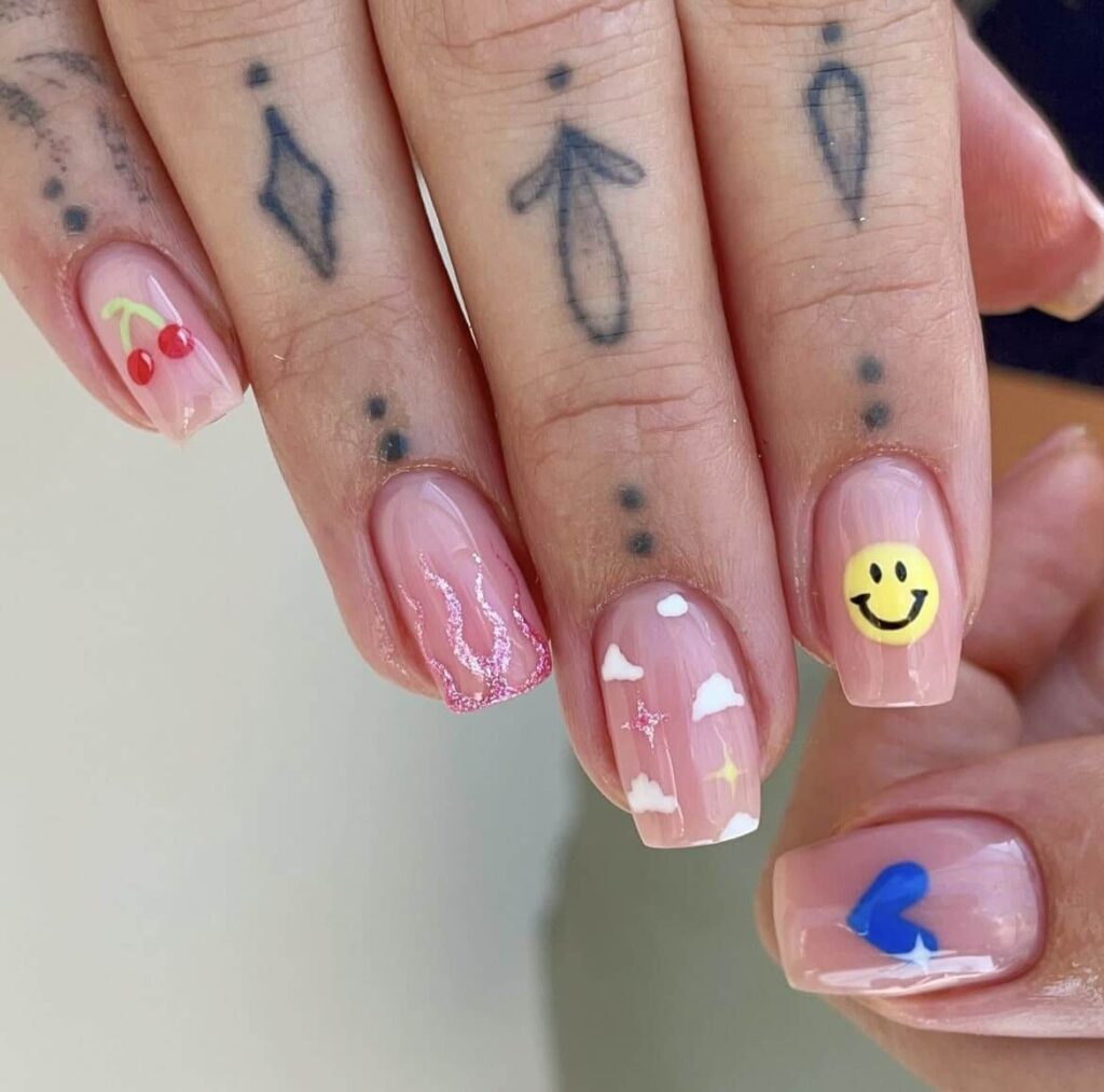 Cheerful and fun design with a mix of different nail art including cheery, flame, cloud, and smiley face on a neutral nude base. by jodiesbeaute