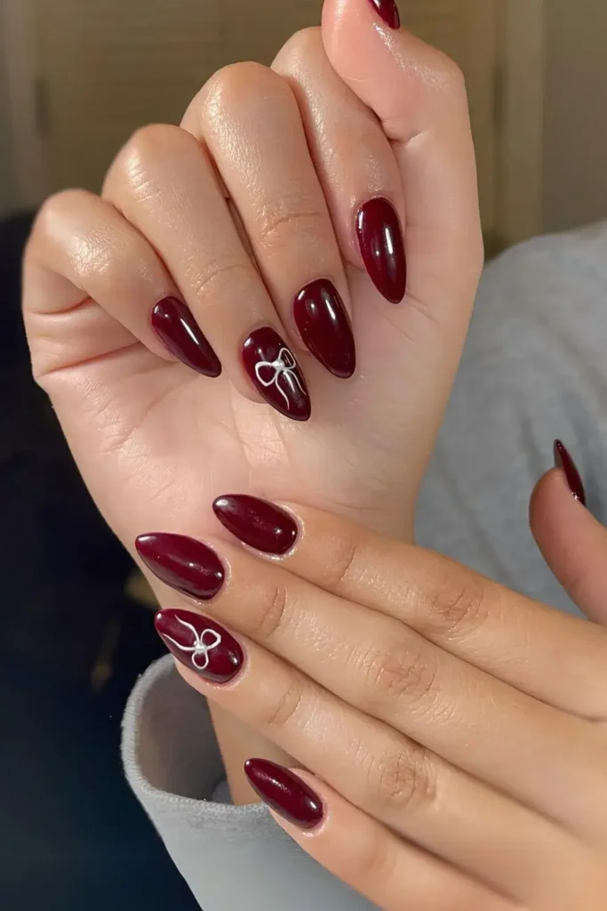 Cherry mocha colored manicure with a tiny white bow on an accent nail. by nailbeautyguide
