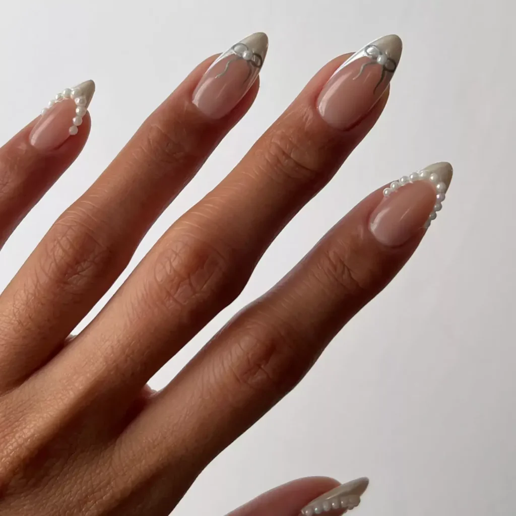Elegant white nails with delicate bows and pearl accents. by overglowedit