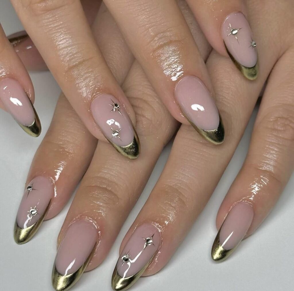 French tip design with a golden chrome finish and star-shaped rhinestones. by manicuresbymo
