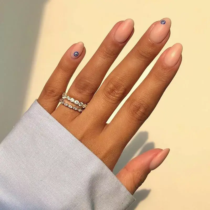 Image of clear nails with a single, tiny evil eye decal or painting placed near the base. by iramshelton