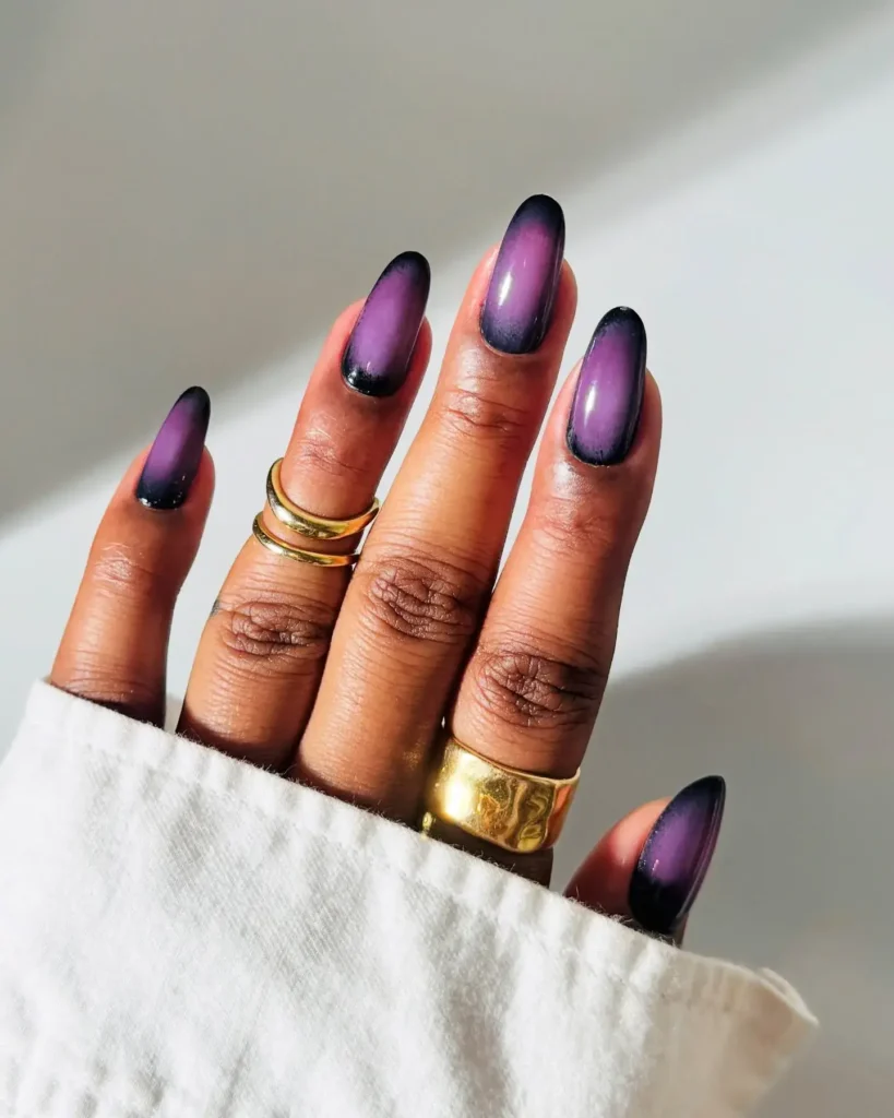 Image of nails with a black base featuring a diffused, lighter purple circular center. by brushedbyb_