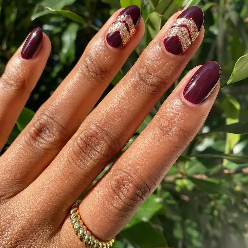 Image of nails with a dark berry base colour and a sharp V-shaped chevron design at the tip in silver glitter. by lolo.nailedit