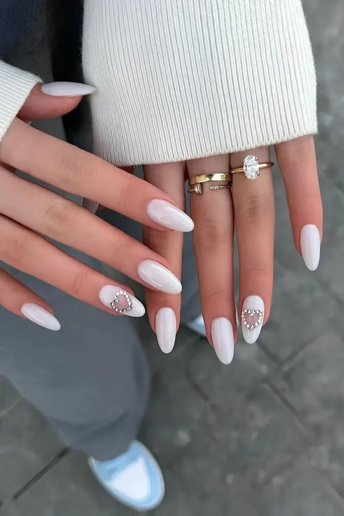 White nails with rhinestones stacked into a heart shape on accent nails. by heluviee