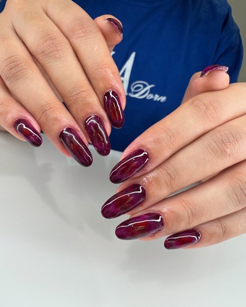 Rich burgundy nails with shimmery metallic squiggles by nailsbymallikaa